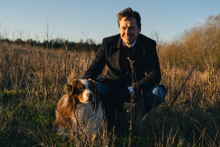 EU-parlamentariker Niels Fuglsang sidder i græs med hund ved sin side