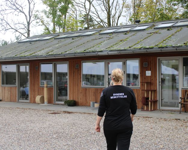 kvinde i sort tøj går mod internatsbygning