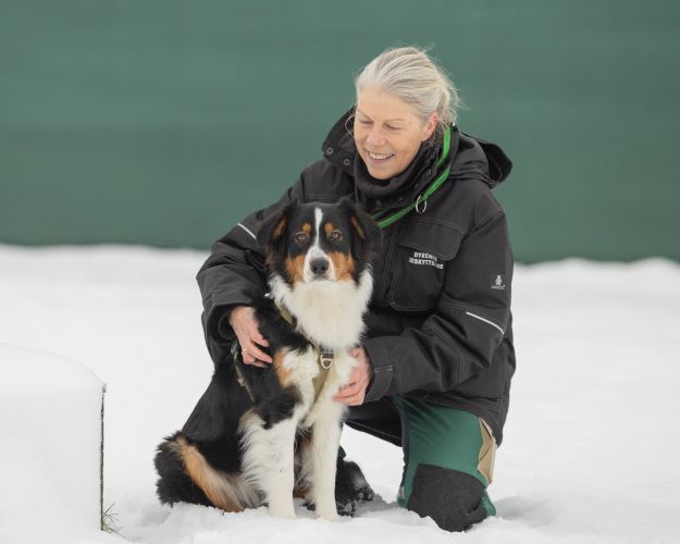 kvinde sidder med hund i sneen