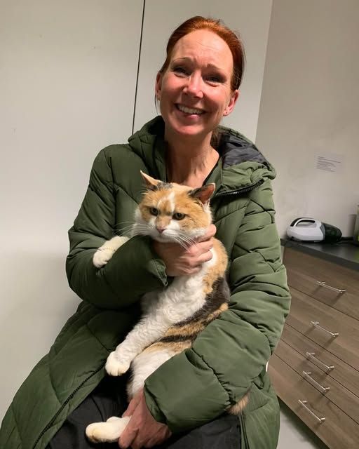 Siden Emma sidst var hos sin ejer, er hun blevet en ældre kat på 18 år. Foto: Privat kvinde med rødt hår og grøn dunjakke sidder med kat på skød