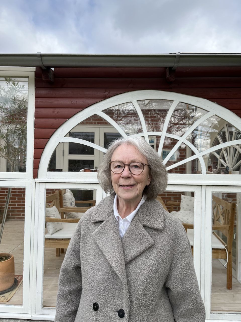 Kirsten Pilegaard Andersen fra Egå, 78 år, pensionist. Foto: Privat kvinde i grå jakke står foran vindue
